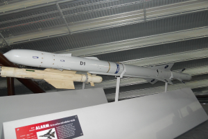 Raketen werden mit einer weißen Tafel am Boden gezeigt, die ein rotes und graues Plakat mit Text auf der linken Seite und ein weißes Dach oben aufweist.