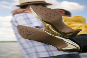 Frau in High Heels mit Datumsangaben darauf, mit einer Person, die eine andere Frau an der Taille hält