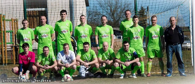 Gruppe von Männern in grünen T-Shirts auf einem Fußballfeld in der Nähe eines Torpfostens mit einem Ball davor.