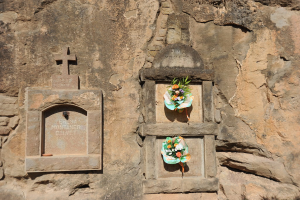 Memorials in die Wand gemeißelt mit Blumensträußen davor.