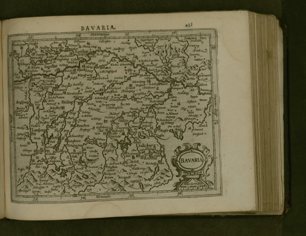 Offenes Buch mit detaillierter Karte von Bayern mit beschrifteten Städten und Ortschaften, begleitet von Text, der die Region beschreibt.