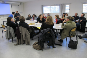 Eine Gruppe von Menschen, die diskutieren, mit zwei Personen im Hintergrund, die sich unterhalten.