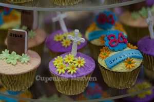 Ein Buch und ein heiliges Kreuzsymbol liegen auf einem Cupcake, mit anderen Cupcakes im Hintergrund sichtbar.