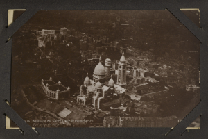 Schwarz-weiß-Foto einer Stadt mit einem großen zentralen Gebäude, das von kleineren Gebäuden umgeben ist.