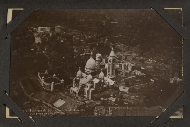 Schwarz-weiß-Foto einer Stadt mit einem großen zentralen Gebäude, das von kleineren Gebäuden umgeben ist.