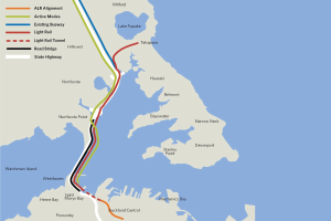 Karte einer Stadt mit einer roten Linie, die eine vorgeschlagene Bahnroute markiert, einschließlich Haltestellen und Details der Umgebung.