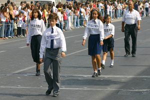 Eine Gruppe von Menschen, die auf einer Straße gehen und Abzeichen auf ihren Hemden tragen, mit einer großen Menge, die sich um die Straße versammelt.