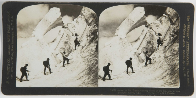 Schwarzes und weißes Foto von Menschen, die einen schneebedeckten Berg mit den Eisschritten des Mt. Blanc im Hintergrund erklimmen, mit Rucksäcken und Seilen.
