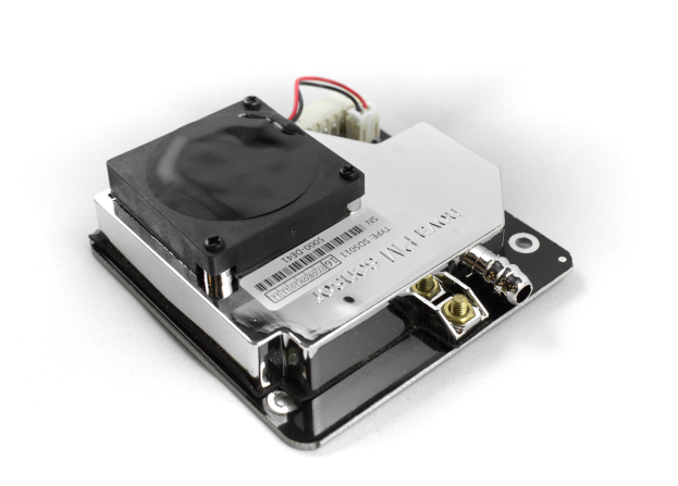 Nahaufnahme eines schwarzen und silbernen Kühlkörpers auf einer weißen Oberfläche mit mehreren daran angeschlossenen Drähten.