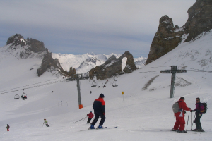 Menschen in Pullovern fahren auf der Eisbahn Ski, mit Seilbahn, Bergen und bewölktem Himmel im Hintergrund.