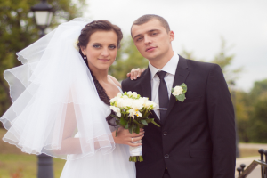 Ein Mann und eine Frau in Hochzeitskleidung stehen zusammen, wobei die Frau Blumen in den Händen hält.