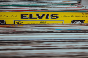 Ein ordentlicher Stapel Elvis-Presley-Platten mit sichtbaren Titeln auf einem leicht unscharfen Hintergrund.