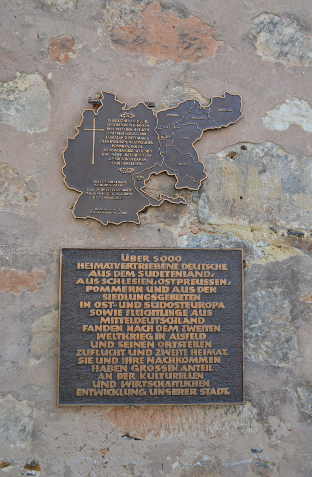 Metallplatte auf einem Steinwall mit einer Deutschlandkarte und eingraviertem Text