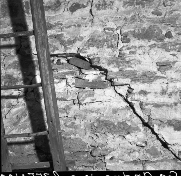 Schwarz-weißes Foto einer hölzernen Leiter, die an einer zerbrochenen Wand lehnt, mit Text am unteren Rand.