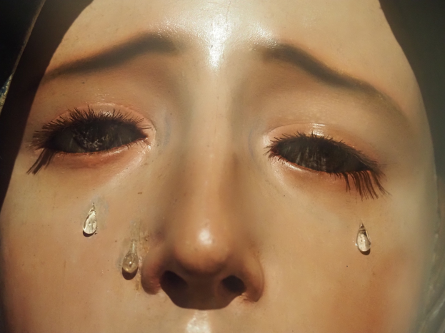 Eine Frau mit Tränen auf den Wangen, ihr Gesichtsausdruck zeigt Trauer.