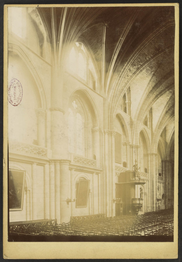 Alte Fotografie eines Kircheninneren mit Bögen, Säulen, Rahmen an den Wänden und einem detaillierten Deckengewölbe, mit verstreuten Objekten, die seinen historischen Prunk betonen.