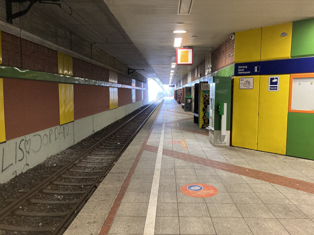 Ein Bahnsteig mit einem Zug auf den Schienen, beleuchtet von Deckenlampen, mit Graffiti an der linken Wand und einigen Gegenständen auf der rechten Seite, identifiziert als Berlin Hauptbahnhof in Berlin, Deutschland.
