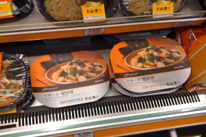 Essensboxen auf Regalen mit Preiszetteln.