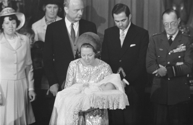 Königin Elizabeth II hält das neugeborene Prinz Andrew mit Prinz Philip, der in formeller Kleidung neben ihnen steht.