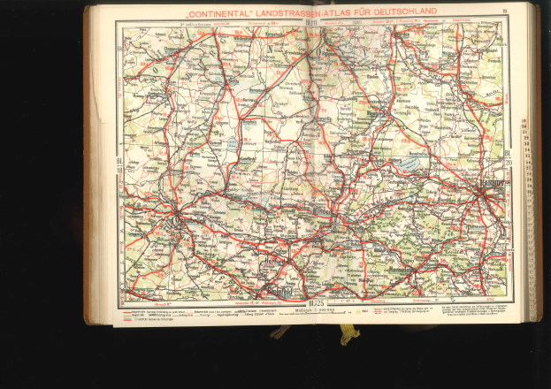 Offenes Buch mit detaillierter Karte von Deutschlands Straßen und Autobahnen auf schwarzem Hintergrund.