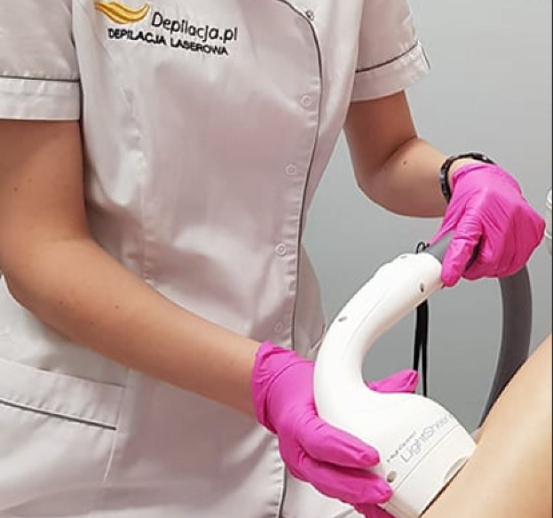 Eine Frau in einem weißen Hemd und pinken Handschuhen bedient eine weiße Laser-Haarrentfernungsmaschine an einer Wand.