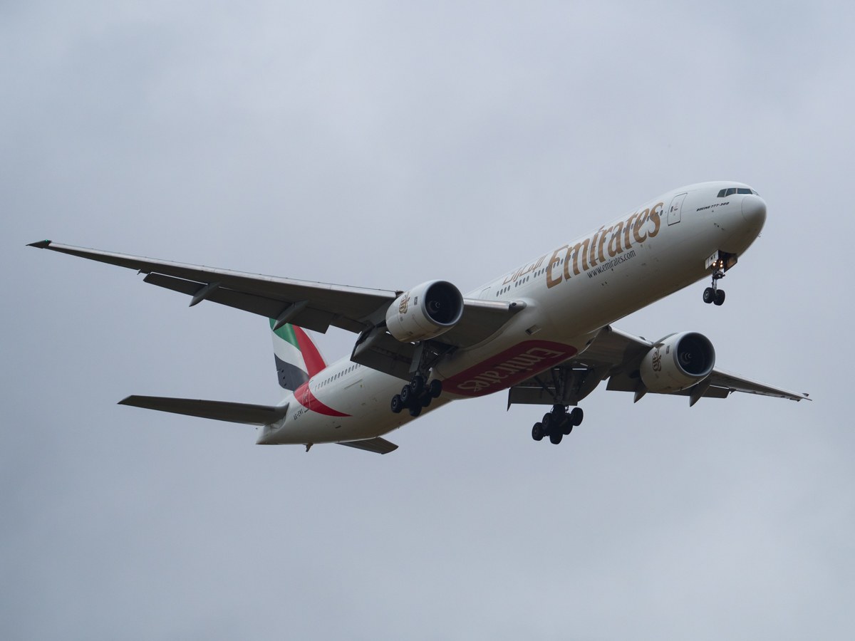 Emirates Airbus A330-300 im Flug, zeigt weiße, rote und grüne Lackierung gegen einen blauen Himmel.
