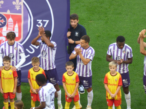 Gruppe junger Jungs auf einem Fußballfeld mit einem Banner im Hintergrund.