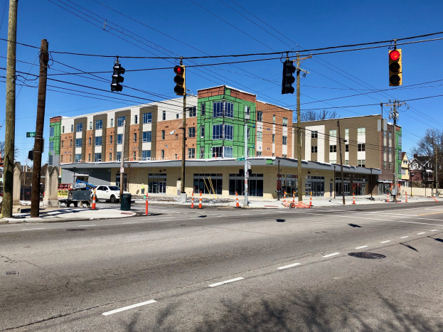 Stadtstraßenszene mit Ampeln, Strommasten, Fahrzeugen, Bäumen, Gebäuden und einer Baustelle im Vordergrund.
