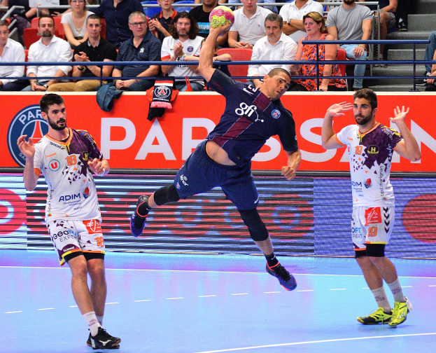 Mannergruppe spielt Handball auf einem Court mit einem Ball im Spiel, Zuschauern im Hintergrund und verstreuten Kleidungsstücken, mit einer Fahne für das Futsal-Weltmeisterschaft 2015-Spiel zwischen Paris Saint-Germain und Olympique Lyon.