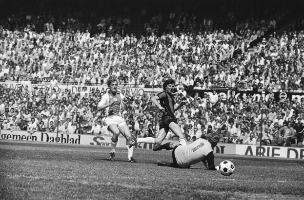 Schwarzes Foto von Männern, die Füßball auf einem Feld spielen, mit Zuschauern im Hintergrund und einem Banner mit der Aufschrift "Bundesliga 1978-79 Ajax 1-1 Hannover 96."