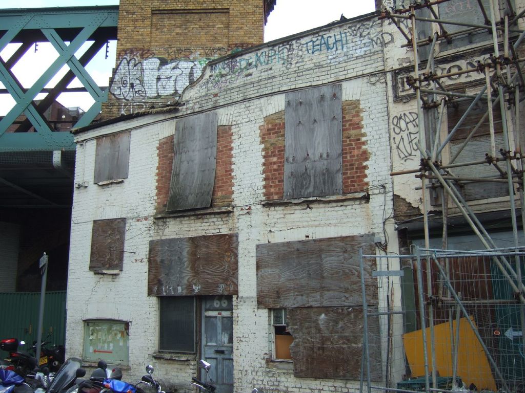 Ein Hausaufbau in der Mitte, Fahrzeuge unten, ein Pfahl links, eine Brücke oben und ein hölzerner Bambusaufbau rechts.