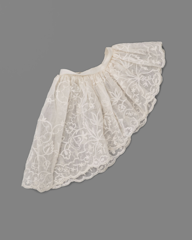 Weiße Röcke mit zarter Spitze-Überlagerung auf grauem Hintergrund, mit leichtem Stoff und feiner, kleiner Nähmuster.