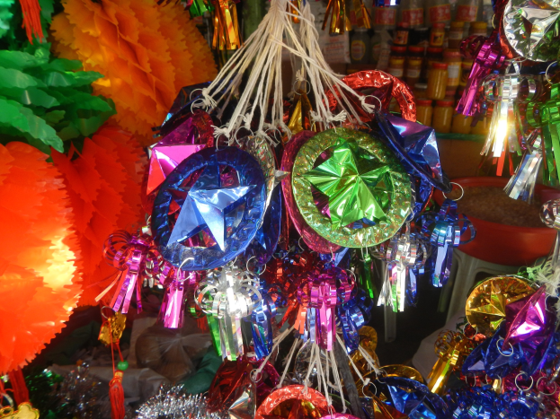 Farbenfrohe Festschmuck, darunter Laternen und Bänder, hängen von der Decke über Regalen mit Flaschen in einer festlichen Atmosphäre.