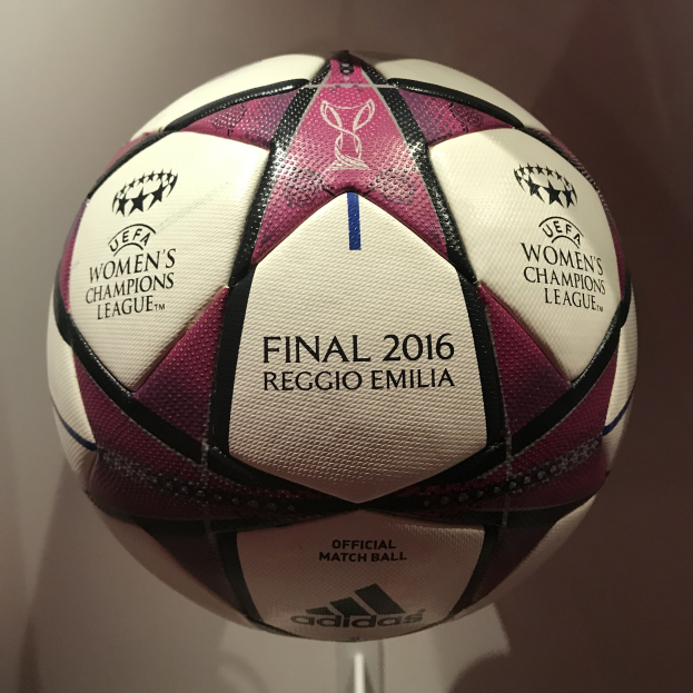 Ein Fußball mit der Aufschrift 'UEFA Women's Champions League Final 2016' in Weiß, Rosa und Schwarz, der auf einem weißen Tisch liegt.