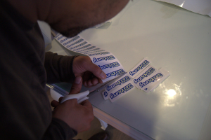 Eine Person schneidet Papier mit einer Schere auf einem Tisch mit einer Glasplatte in kleine Stücke.