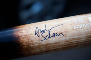 Ein Nahaufnahme eines hölzernen Hockey-Schlägers mit einer Signatur und Text, wahrscheinlich der Name des Spielers.