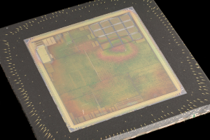 Nahaufnahme eines rechteckigen Halbleiterchips mit metallischem Glanz, dünnem Metallrahmen und kleinen Kantenlöchern auf schwarzem Hintergrund, mit leicht erhöhten Kanten.